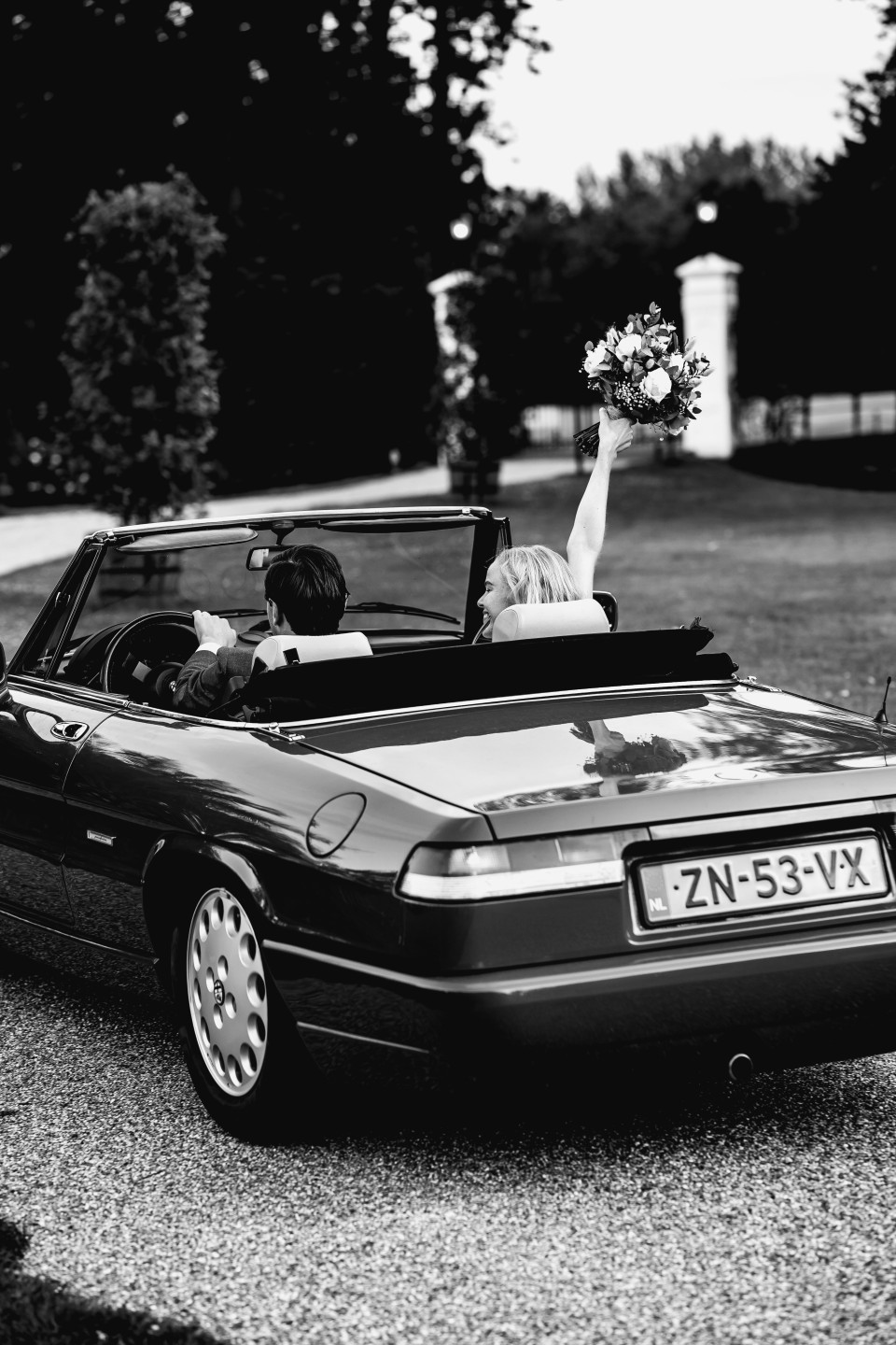 een zwart-wit foto van een stel in een cabriolet auto