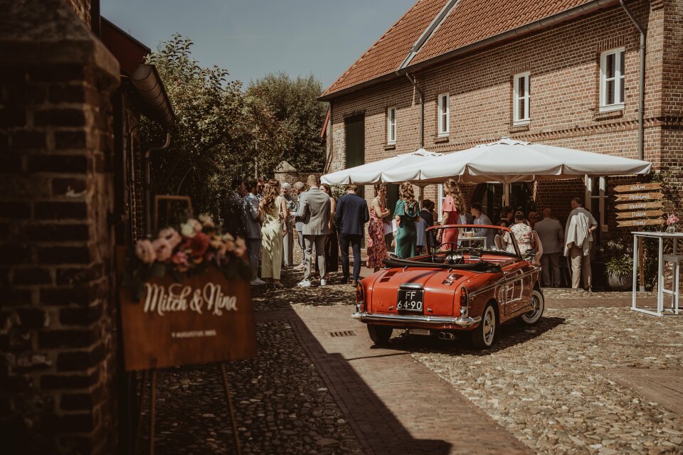 een rode auto geparkeerd voor een groep mensen