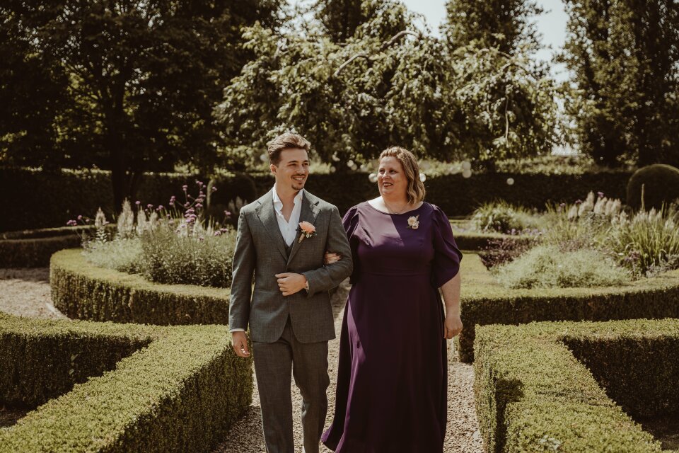 een man en een vrouw die in een formele tuin wandelen