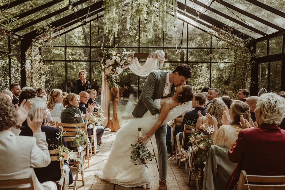 het pasgetrouwde stel dat aan het eind van hun huwelijksceremonie kust