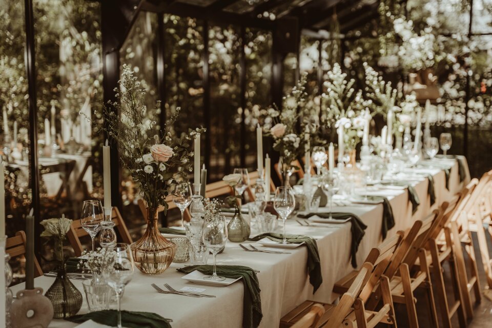 een lange tafel ingericht met kaarsen en bloemen