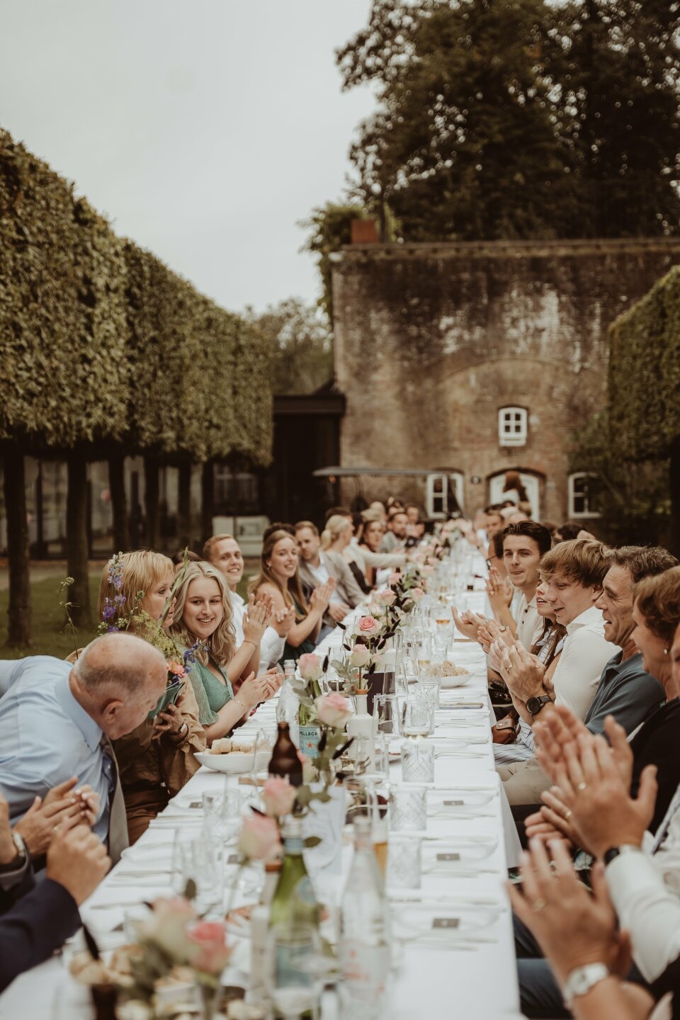 een grote groep mensen die aan een lange tafel zitten