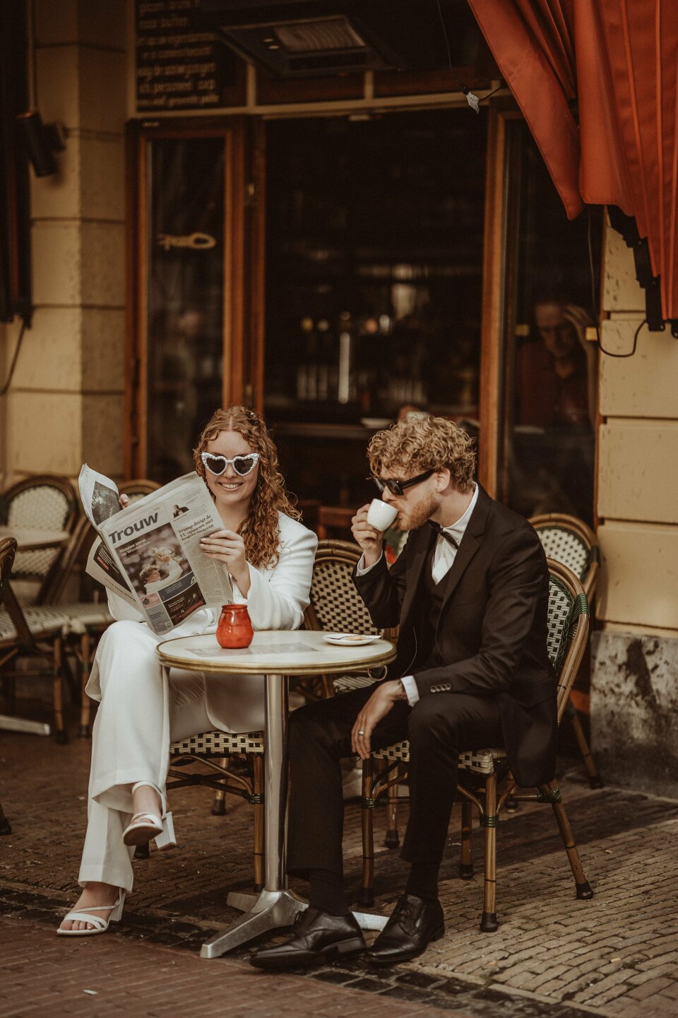 een man en een vrouw die aan een tafel zitten en een krant lezen