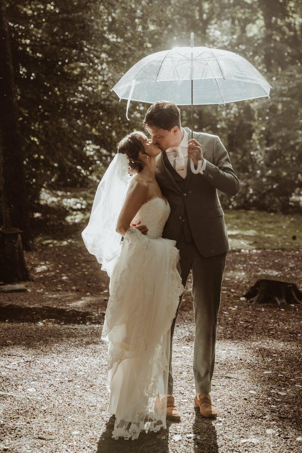 een bruid en bruidegom die kussen onder een paraplu