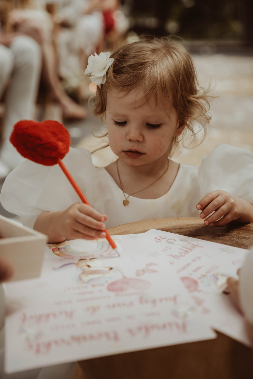 een klein meisje dat aan een tafel zit en op een stuk papier tekent