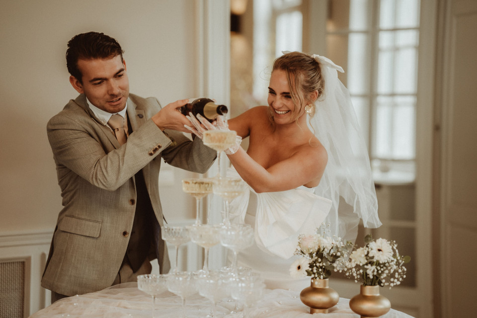 een bruid en bruidegom schenken champagne in glazen