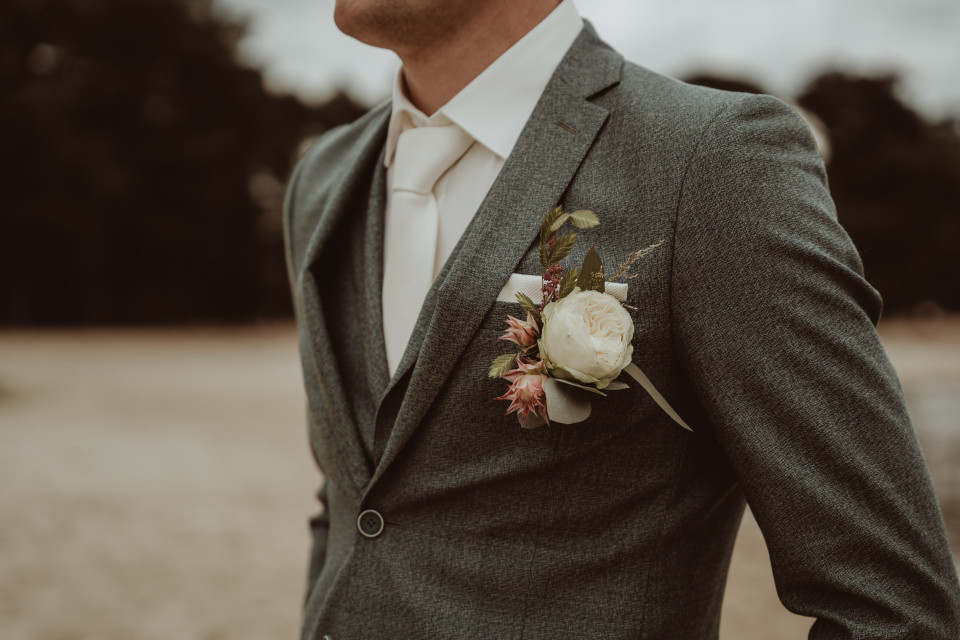 een man in pak en stropdas met een bloemenboutonnière