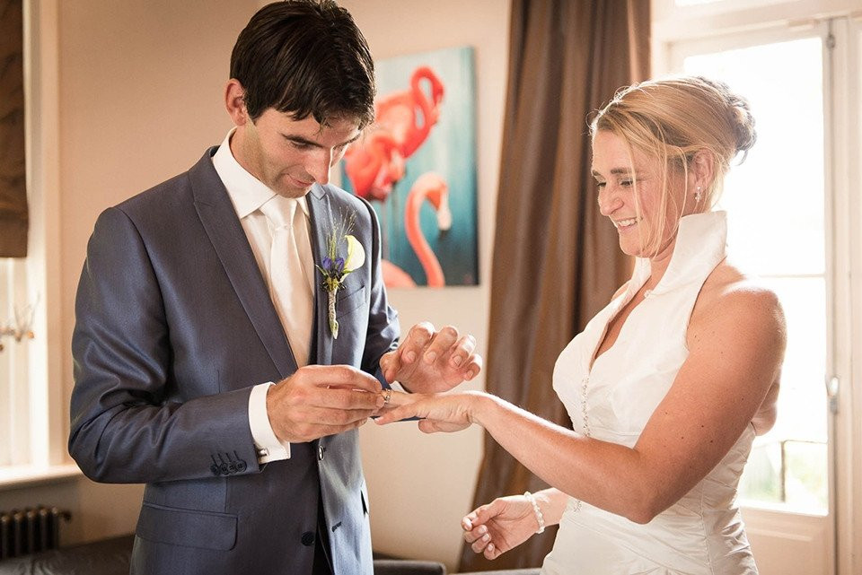 een man en vrouw in trouwkleding die een trouwring omdoen