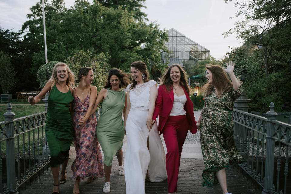 bridesmaids in groene jurken lopen over een brug