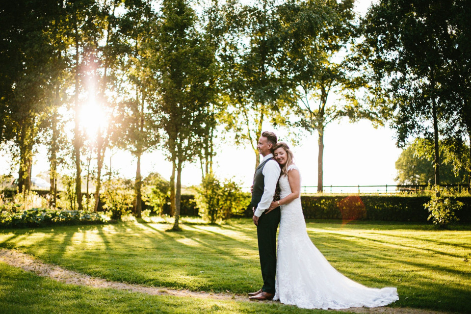 een bruid en bruidegom poseren voor een foto in de zon