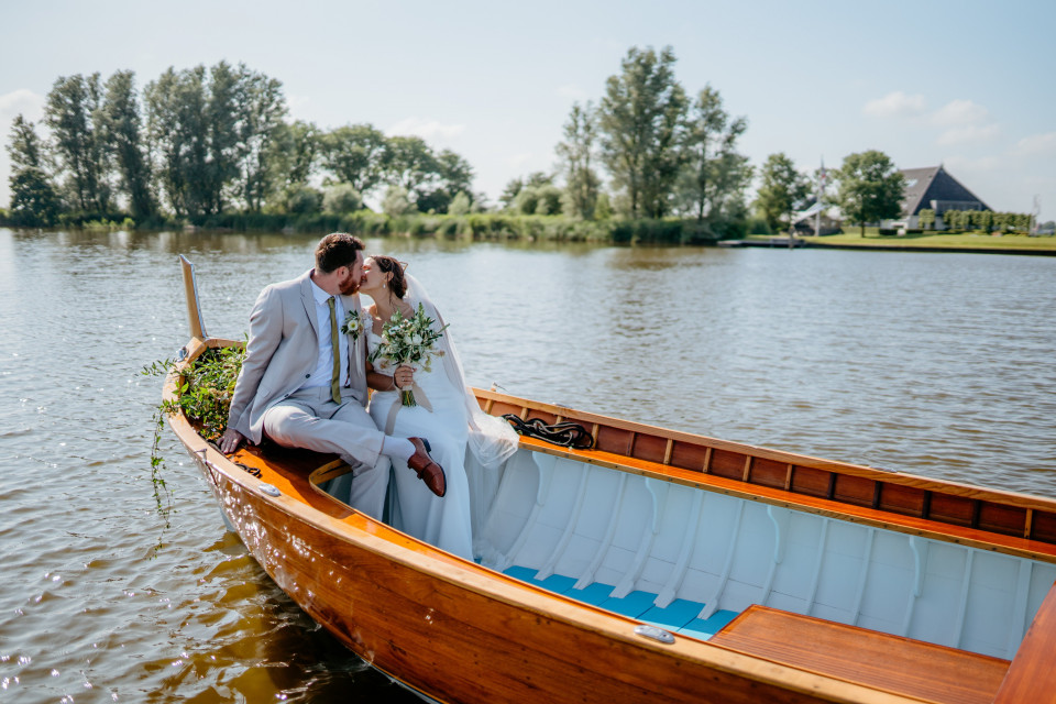 een bruid en bruidegom zitten in een boot op het water