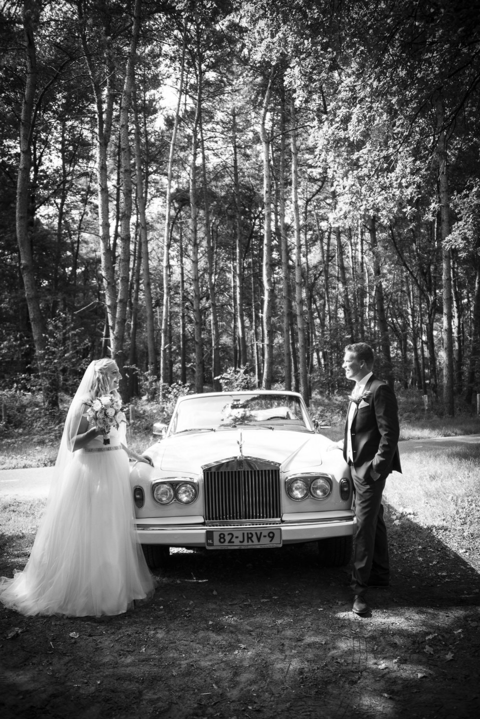 een bruid en bruidegom staan naast een vintage auto