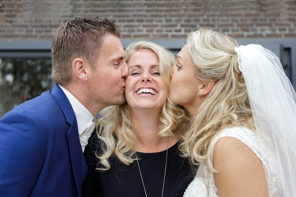 een bruid en bruidegom kussen terwijl de bruid glimlacht