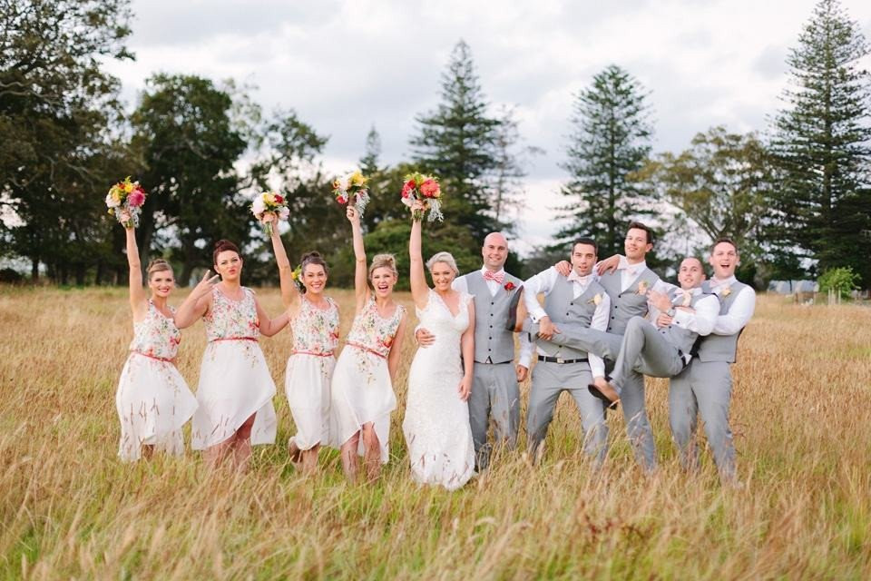 een bruiloftsfeest in een veld met hun armen in de lucht