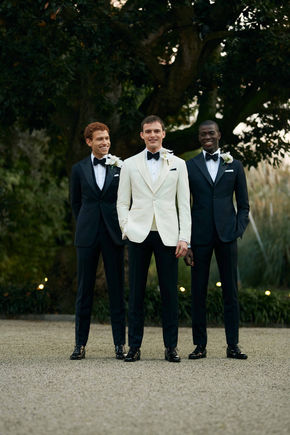 drie mannen in smokings staan samen voor bomen
